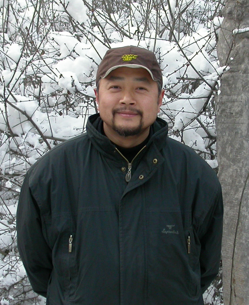 A person in winter clothing standing in front of snow-covered trees